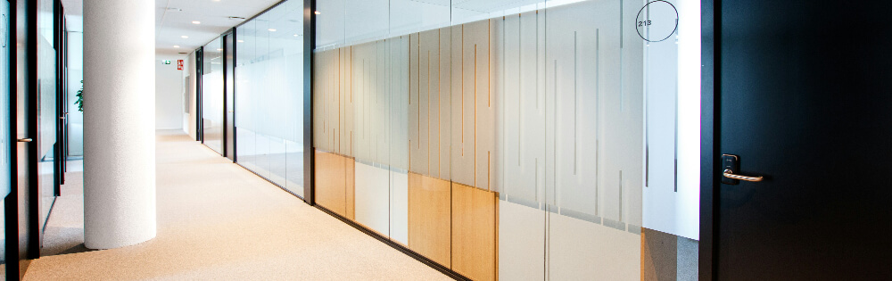 Moderner Büroflur mit Glaswänden, Holztüren und heller Beleuchtung.